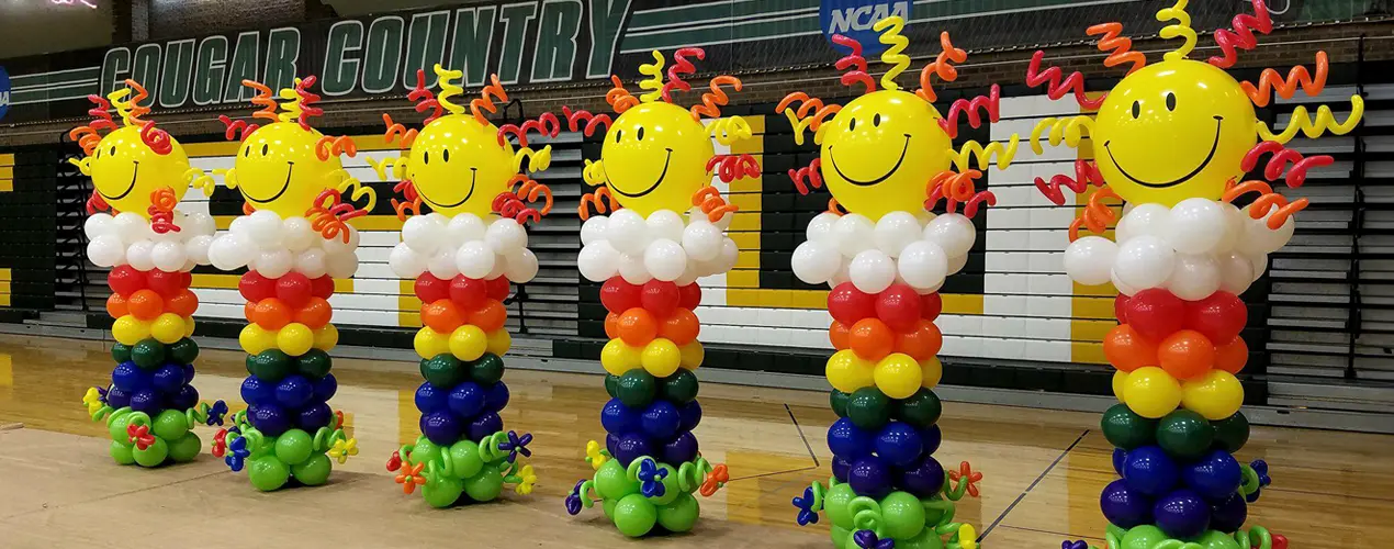 Sun topped balloon columns in a school gym.
