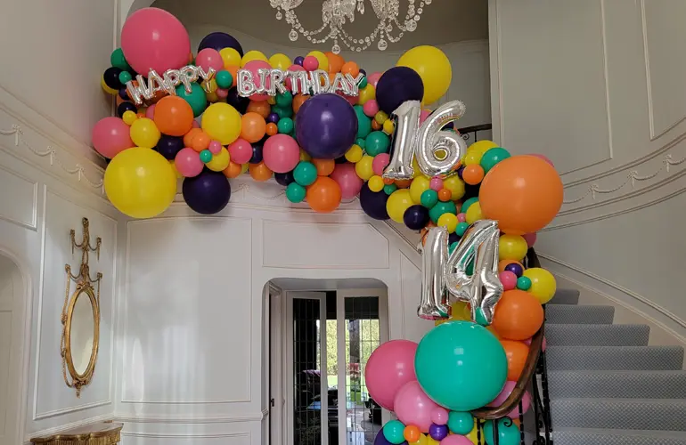 Organic balloon garland on staircase for birthday celebration