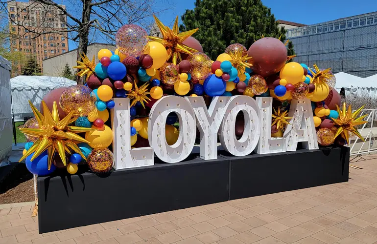 Organic balloon garland on Alpha-Lit lettering for Loyola University event