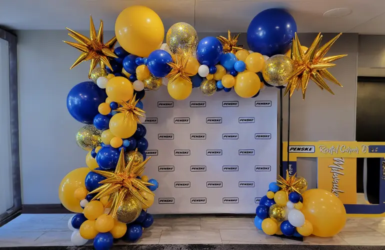 Organic styled trendy balloon arch in front of a step and repeat for a corporate hiring event