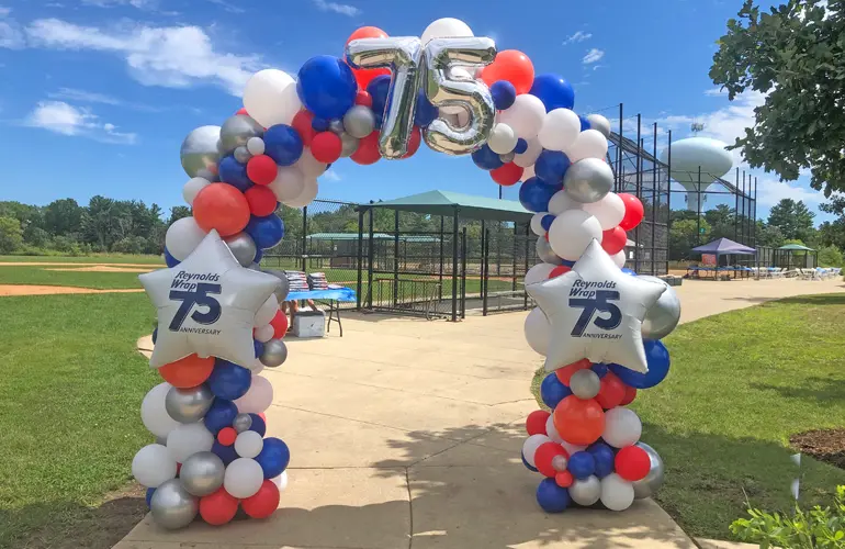 8ftx8ft Outdoor organic balloon arch with custom foil balloon accents to celebrate the company's 75th anniversary.