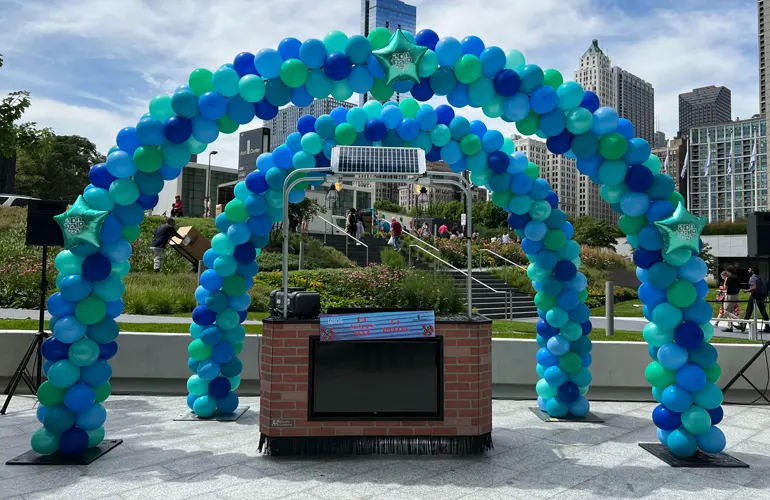 Outdoor balloon arches over DJ area for a company party