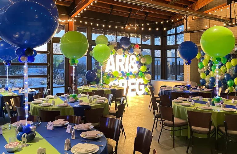Full room balloon setup with centerpieces, photo backdrop and organic garland on Alpha-Lit lettering