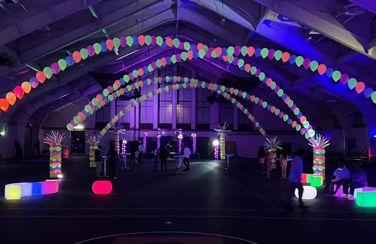 Neon blacklight balloon arches in high school gym