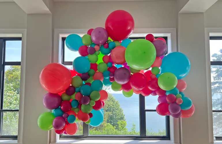 Rainbow balloon arch with balloon bouquets in office lobby