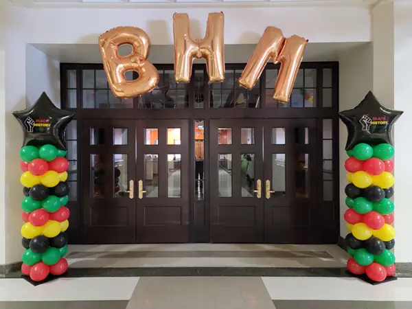 Balloon columns with BHM foil letters creating an arch for Black History Month