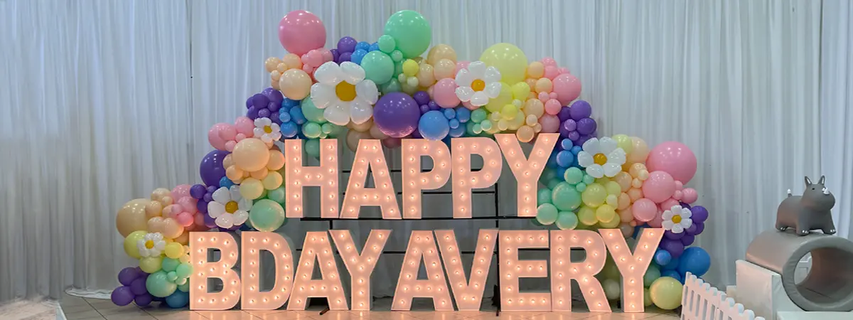 Organic balloon garlands with flower balloon accents on Alpha-Lit light up lettering