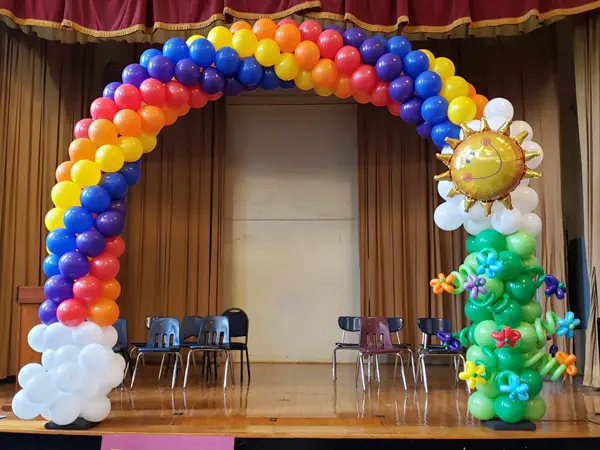Classic 8ftx8ft balloon arch in a spiral rainbow pattern with balloon flower accents