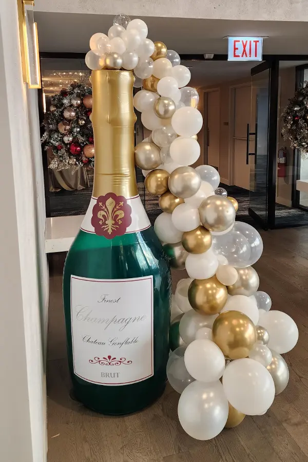 Giant champagne bottle with an organic balloon garland flowing out of the top
