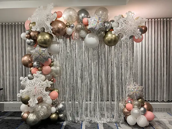 Foil snowflake balloons accenting a metallic backdrop wall