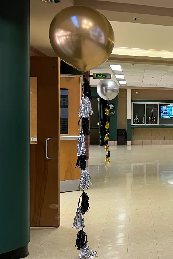 A jumbo helium balloon with a stand of metallic tassels