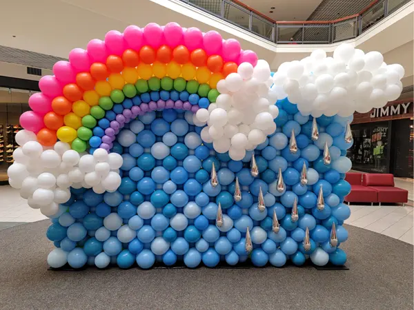 Welcome the beauty of nature with this balloon wall featuring a rainbow and raindrops