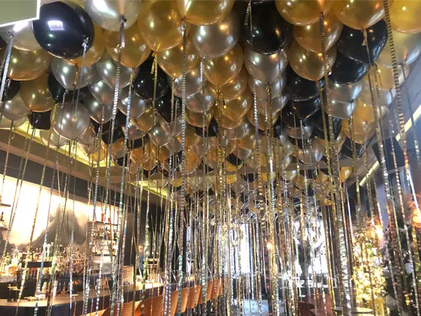 Create a magical atmosphere with a ceiling full of balloons on metallic streamers