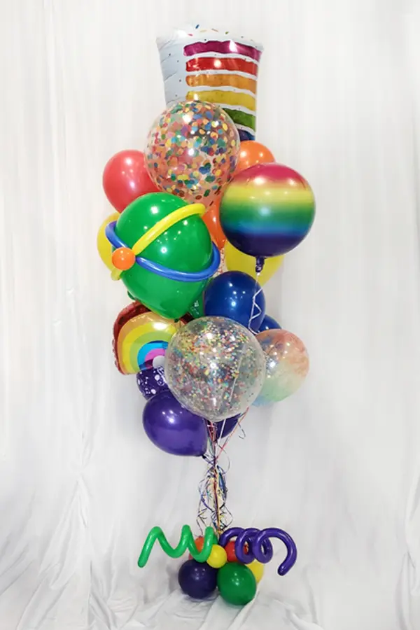 A large balloon bouquet in rainbow colors featuring rainbow foil balloons and confetti balloon accents