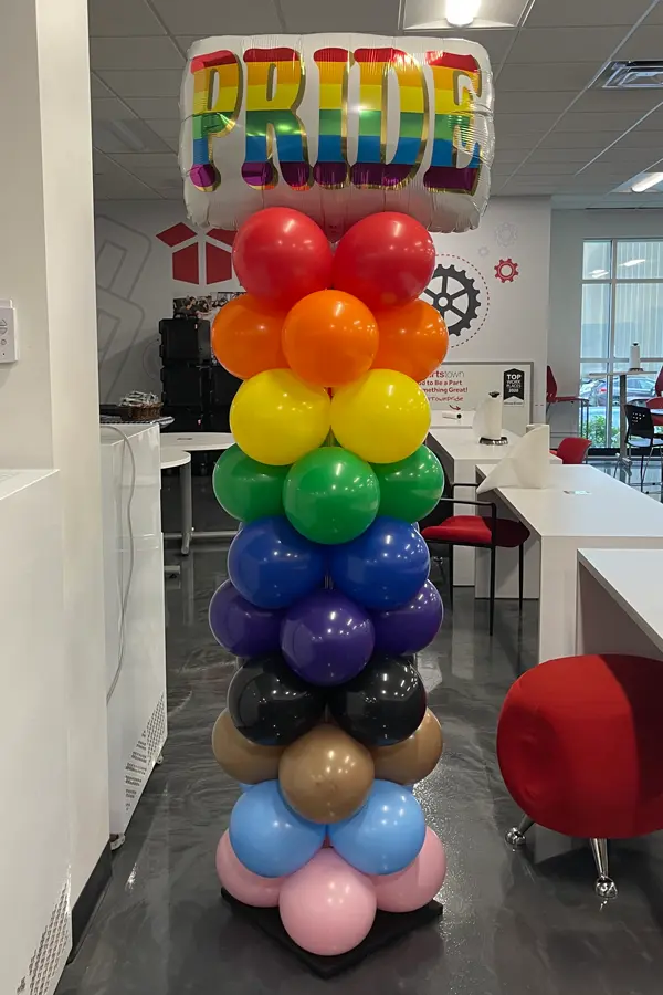 7.5ft tall classic balloon column in progressive pride color pattern with foil balloon topper