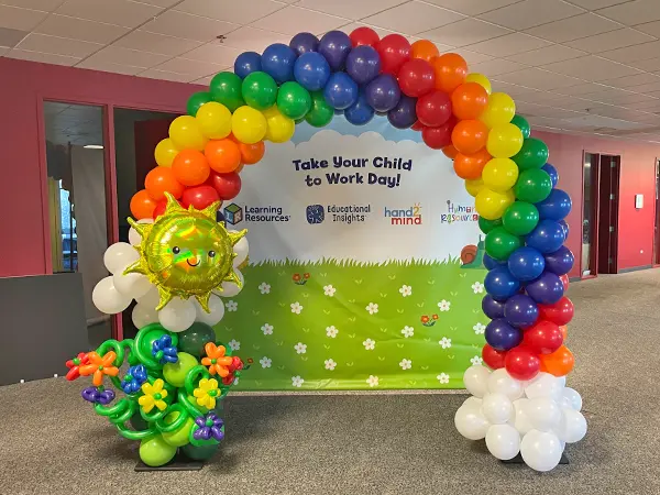 Classic style balloon arch in a rainbow pattern with a sun and flower accents