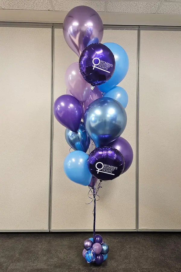 Balloon bouquet of mixed balloon sizes, colors, and styles featuring the Women's History Month logo